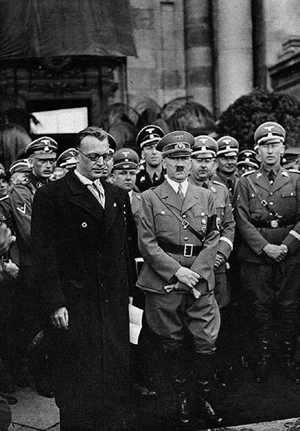 Na segunda-feira, 14 de março de 1938, Hitler chegou aplaudido a Viena, onde foi recebido pelo advogado nazista Seyss-Inquart, que assumira o governo da Áustria na véspera. Reinhard Heydrich, Heinrich Himler e Martin Bormann (da direita para a esquerda), principais chefes da SS e que foram os organizadores das espoliações de bens e demais violências contra judeus, aparecem na foto atrás de ambos. Foto Heinrich Hoffman – fotógrafo pessoal de Hitler. Bundesarchiv, Bild 119-5243 / CC-BY-SA 3.0.